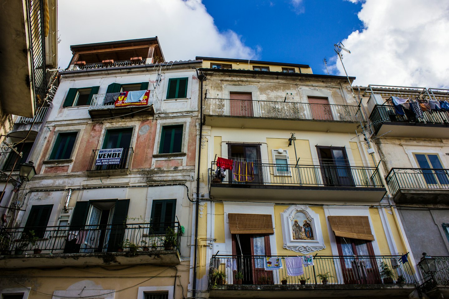 Palazzi con persiane verdi e balconi sotto il cielo blu.