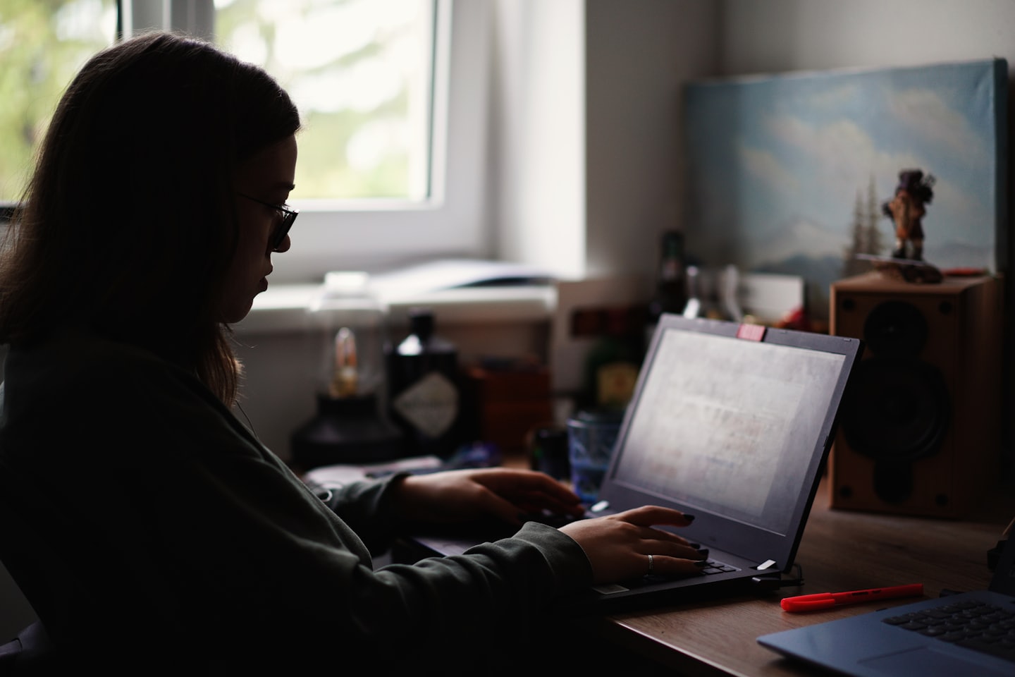 Persona che lavora al computer portatile su una scrivania di legno.