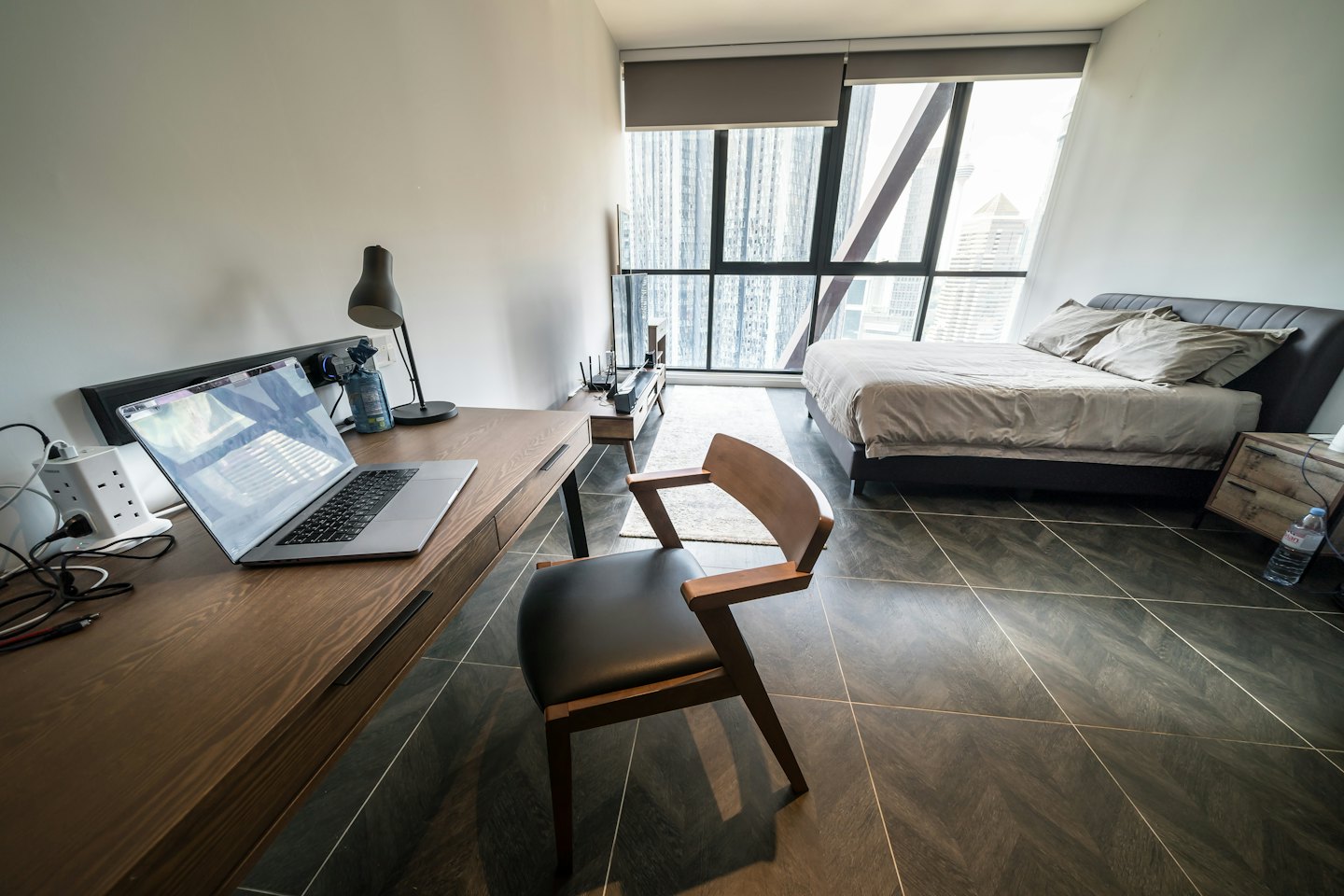 Moderno monolocale con zona lavoro e letto vicino a finestre sulla città.